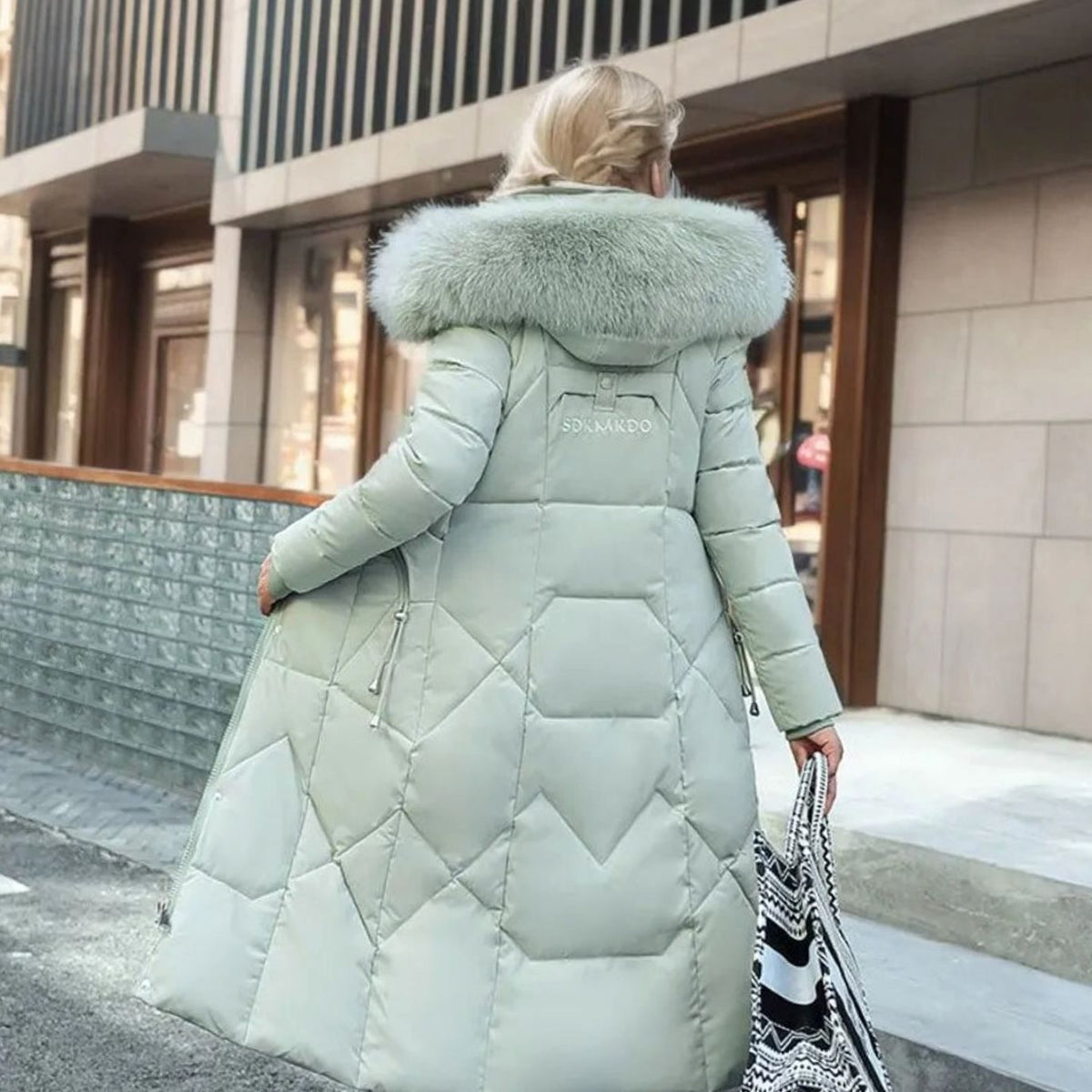 Woman wearing a long cream quilted winter coat with faux fur trimmed hood - view 12
