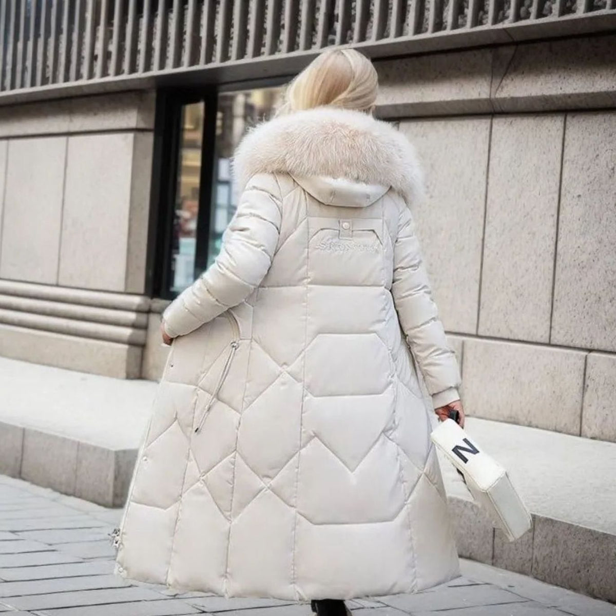 Woman wearing a long cream quilted winter coat with faux fur trimmed hood - view 4