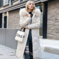 Woman wearing a long cream quilted winter coat with faux fur trimmed hood - view 5