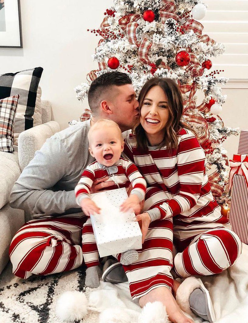 Family wearing matching red and white striped Christmas pyjamas with grey cuffs