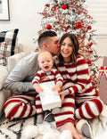Family wearing matching red and white striped Christmas pyjamas with grey cuffs