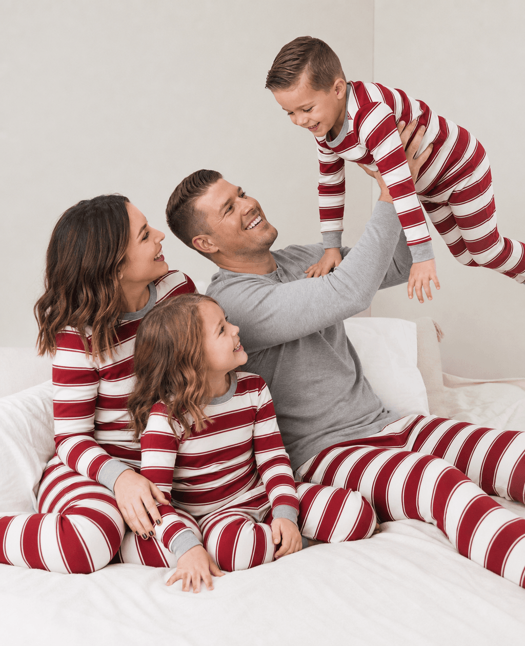 Family wearing matching red and white striped Christmas pyjamas with grey cuffs - view 2