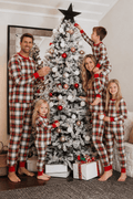 Family wearing matching red and cream tartan Christmas pyjamas with red ribbed cuffs