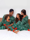 Family in matching green Fair Isle Christmas tree print pyjamas with red cuffs