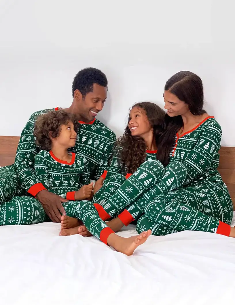 Family in matching green Fair Isle Christmas tree print pyjamas with red cuffs
