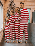 Family wearing matching red and white striped Christmas pyjamas with grey ribbed cuffs