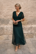 Woman wearing a draped off-shoulder maxi party dress with ruched waist and sheer flowing skirt